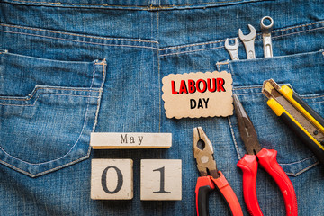 Wooden Block calendar for Labour Day, May 1. Many handy tools with blank space on jeans background texture.