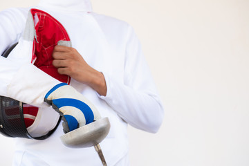 Close-up of a fencer in white fencing suit and holding his mask and a sword on white background