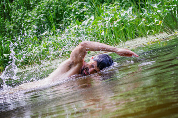The young man Caucasian appearance with a beard swimming in the river