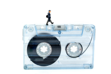 Miniature people : Businessman walking on tape cassette,music learning, education, business concept.