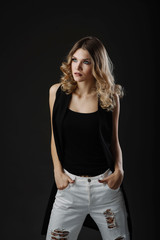 Beautiful fashion portrait of young blonde woman in stylish clothes posing isolated on black background