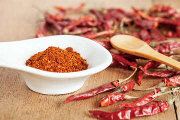 Cayenne pepper in white dish and dried chilli on wood table.