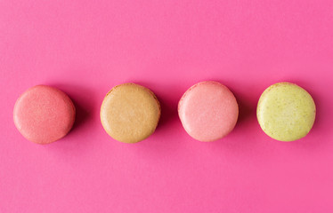 Obraz na płótnie Canvas Colored macaroons on a pink background , colorful almond cookies, pastel colors, vintage card, top view