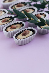 White plates, glasses and utensils on black table, elegant tablewareRow of delicious praline sweets with almonds on purple background