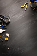 school supplies, alarm, pencils on black chalkboard top view, copy space, vertical framing. concept: back to school background, school's out, school holidays