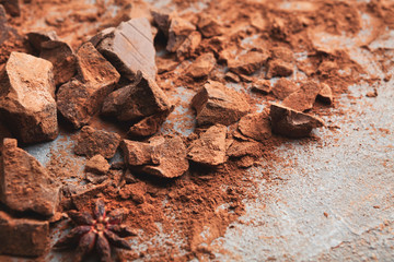 Crushed chocolate pieces and cocoa on gray background