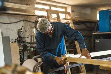 Naklejka na ściany i meble Mid-age gray hair carpenter working in his workshop