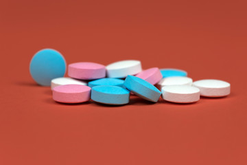 multicolor vitamins drugs pink, blue and white on orange-brown background