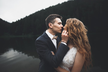 Beautifull wedding couple kissing and embracing near mountain with perfect view