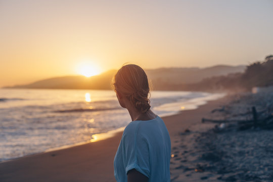 Woman silhouetted at sunset on a beach
