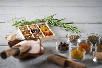 colorful fresh herbs and spices assortment on a white wooden background