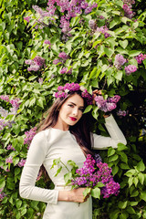 Cheerful young woman with makeup and spring lilac flowers outdoor