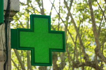 Closeup of a green pharmacy sign outside a pharmacy store in France.