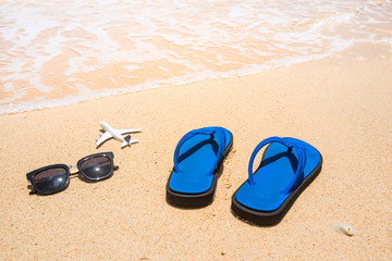 Fototapeta na wymiar Beach, flip flop sandals, sunglasses and airplane. Holidays concept