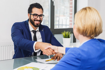 Business colleagues have work contract agreement sitting in white office room, handshake deal concept