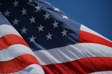 Close Up on American Flag Stars and Stripes Waving against Blue Sky in Afternoon Sun