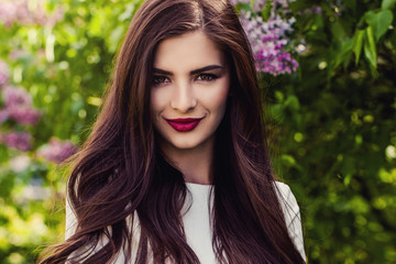 Closeup portrait of cute smiling girl outdoors. Beautiful woman face with long healthy hair and makeup