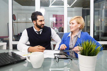 Analytic manager team working process, bearded man and blonde businesswoman dressed in suits work with documents at table with laptop in modern office