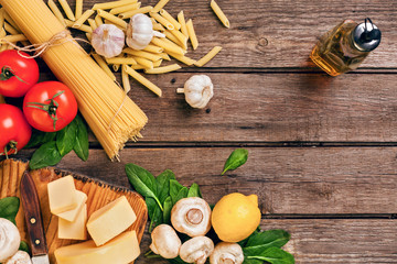 Ingredients for spaghetti with basil, tomatoes, cheese on wooden background, top view, place for text
