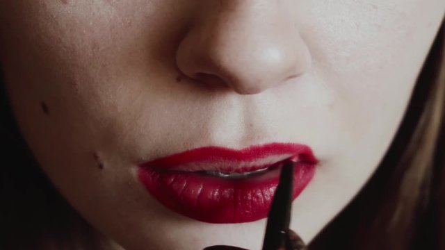 The girl paints her lips with red lipstick. Classic red lips. Close-up. Classic red lips. 4k