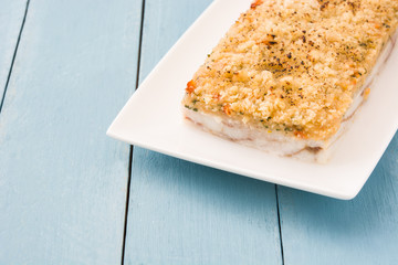 White fish casserole with cheese on blue wooden background. Copyspace