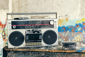 Retro boombox radio with cassettes / Vintage ghetto blaster with plenty of musical cassettes on grungy background with graffiti. - obrazy, fototapety, plakaty