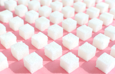 Refined sugar on pink background.Cubes of sweet and white sugar in geometricshape. Hard shadows.