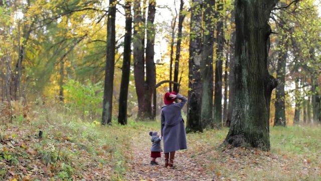 Mom and daughter are walking in the autumn park