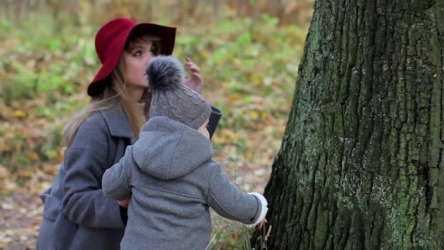 stylish girl with a daughter at an old tree in an autumn park