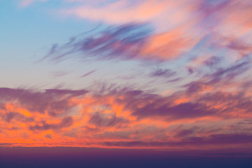 Beautiful cloudscape at scarlet sunset with colorful contrasting cirrus clouds
