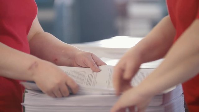 Female hands sorts the stacks of newspapers in typography