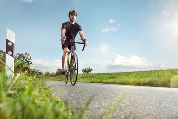 Fototapeta na wymiar Sportlicher Radfahrer auf einer sonnigen Landstraße