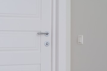 Detail of white interior door with chrome door handle and latch