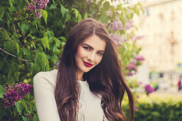 Fototapeta premium Beautiful smiling woman outdoors. Female model brunette with makeup and long healthy hair