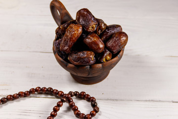 Dates fruit and rosary on white wooden table