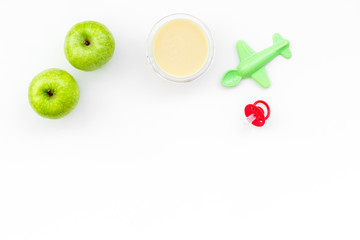 Fruit puree for baby. Jar with food near apple, pacifier, toys on white background top view copy space