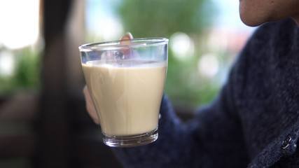 Happy young woman drinking coffee on sunny day sitting outdoors