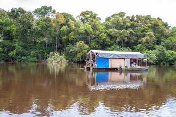 Fototapeta na wymiar Jungleboat: rustikales selbstgebautes Hausboot / Floß aus Fässern und Planen auf dem Amazonas