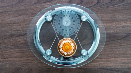 Modern glass and steel scale with a small pastry dieting theme