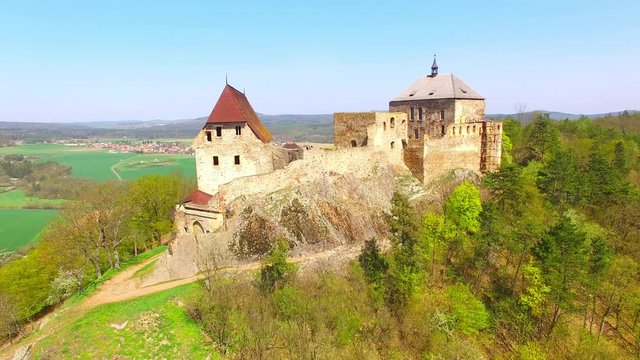 Drone flight around Tocnik Castle in blooming orchard. A royal chateau of Wenceslas IV from the 14th century, adjusted in the Renaissance and the Baroque styles. Famous Czech monument from above. 