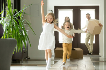 Excited funny kids boy and girl running inside luxury big modern house on moving day, cute children...