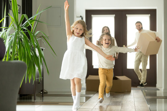 Excited funny kids boy and girl running inside luxury big modern house on moving day, cute children entering exploring new home, happy young family buying real estate, mortgage and relocation concept
