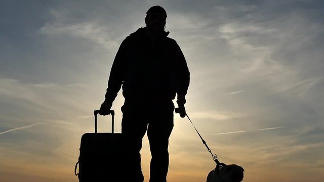 Silhouette of man with suitcase and dog slow motion