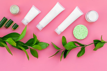 Organic skin care products. Cream, lotion, tonic. oil near green leaves on pink background top view pattern