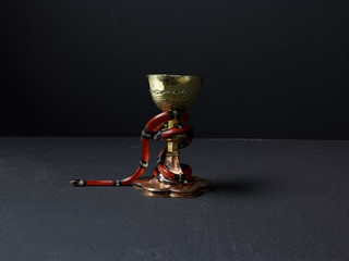 Red snake wrapped around gold chalice
