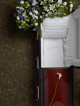 Top view of empty open coffin with floral bouquets