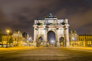 Arc de Triomphe at the Place du Carrousel and Louvre museum in Paris illuminated in the evening