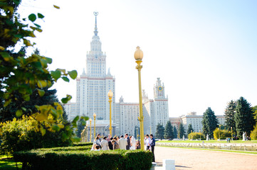 Obraz premium Newlyweds with guests on a walk on the wedding day near the building of the Moscow State University.