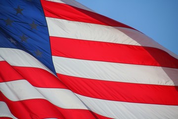 American Flag Waving Against Blue Sky Backlit by Morning Sun