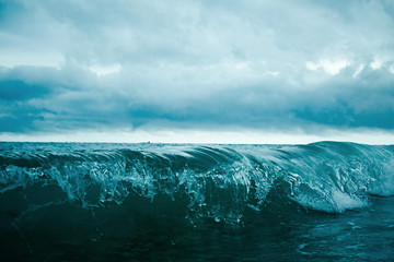 Close-up blue ocean waves under cloudy sky